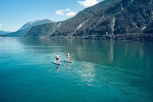 Activiteiten aan het Achenmeer in de zomer Twee mensen op paddleboards op een meer.