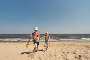 Ein Junge und ein Mädchen rennen am Strand.