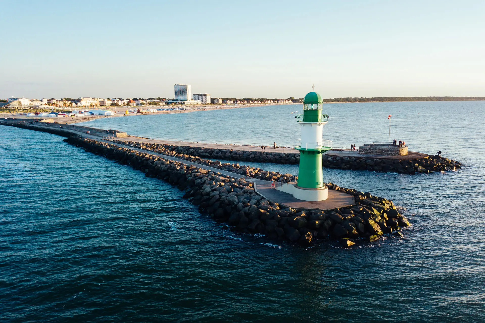 Groene en witte vuurtoren op rotsen in het water.