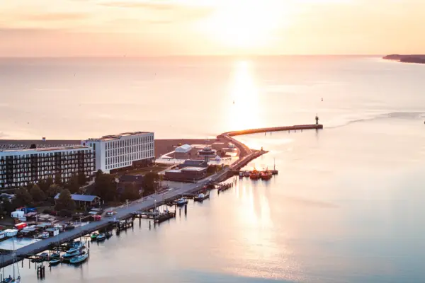 aja Travemünde Das aja Travemünde direkt am Wasser gelegen mit einem Leuchtturm im Hintergrund.