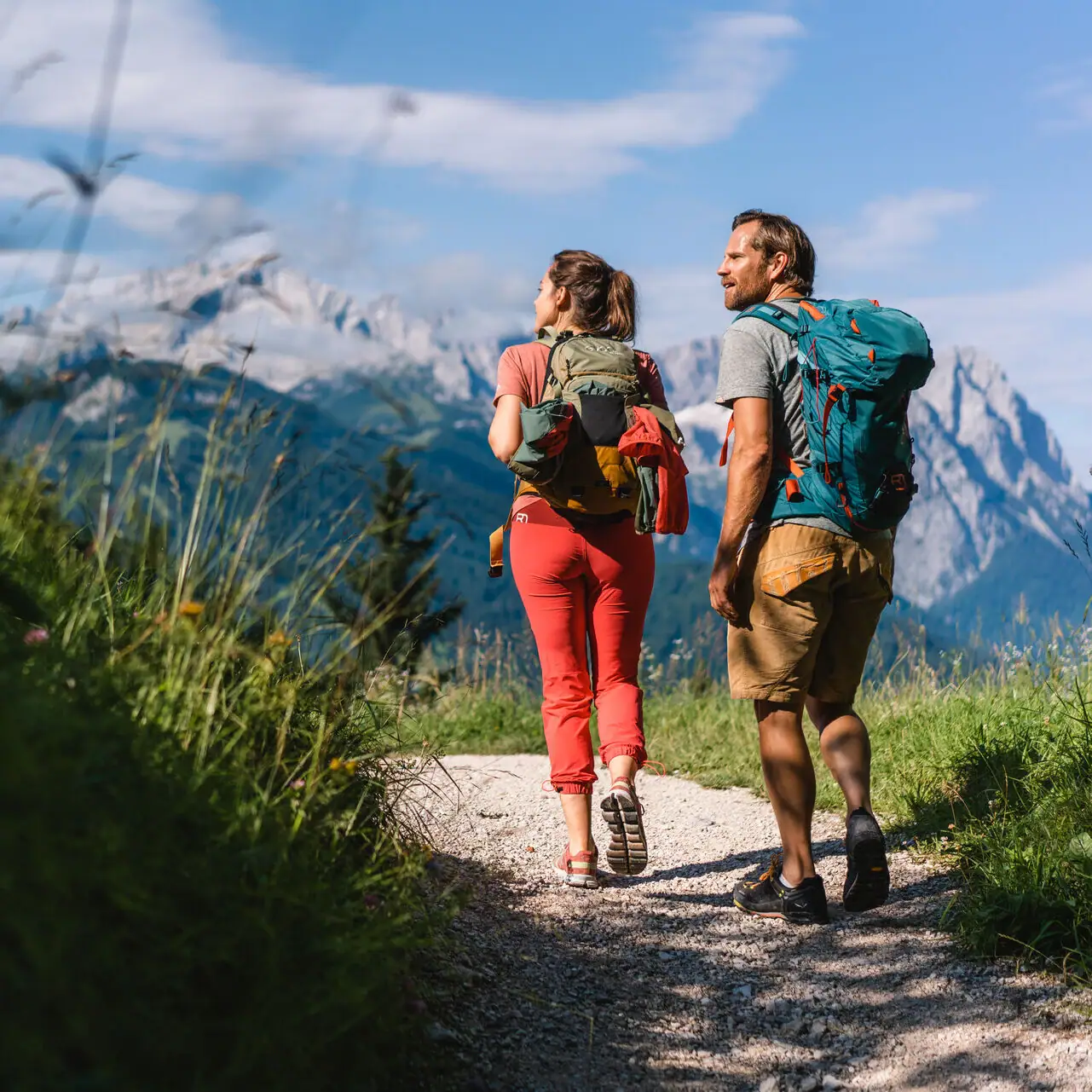 Wandelen Een man en een vrouw lopen over een pad met bergen op de achtergrond.