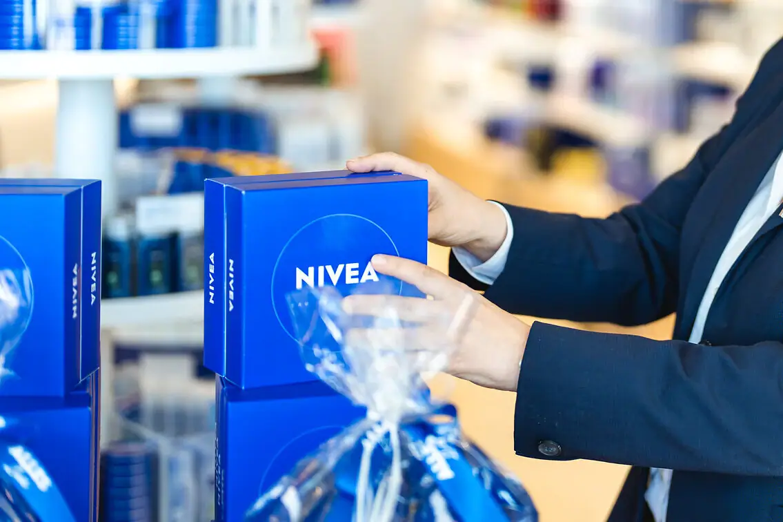 Een vrouw in pak houdt een doos NIVEA vast
