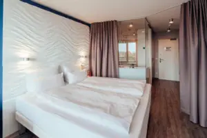 Een bed met witte lakens en een gordijn.