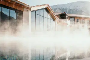 Buitenzwembad Een gebouw aan het water met een berg op de achtergrond.