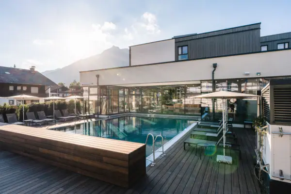 Buitenzwembad Een zwembad met een terras en stoelen.