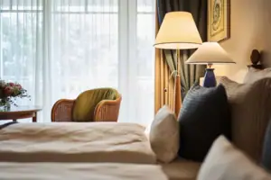 Tweepersoonskamer Een bed met kussens en een lamp naast een raam.