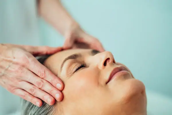 Cosmetica Iemand masseert het hoofd van een vrouw.