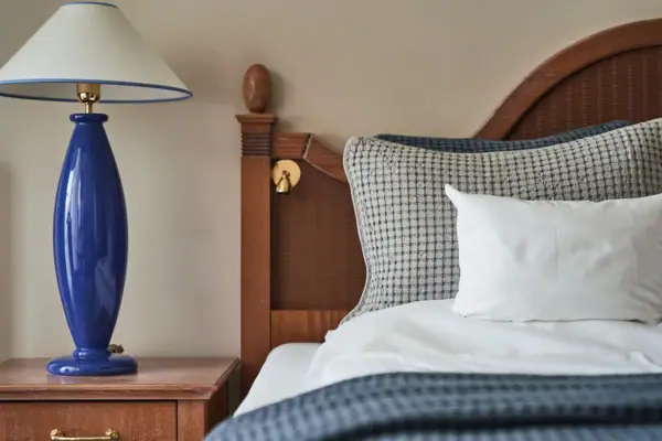 Ein Bett mit einer blauen Lampe auf einem Nachttisch.