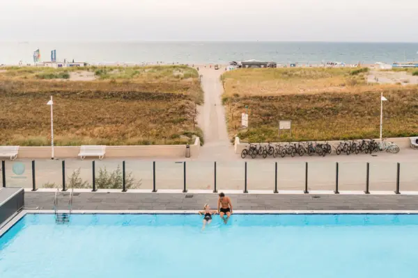 Außenpool Ein Mann und eine Frau am Rand eines Außenpools mit Blick auf den Strand und die Ostsee.