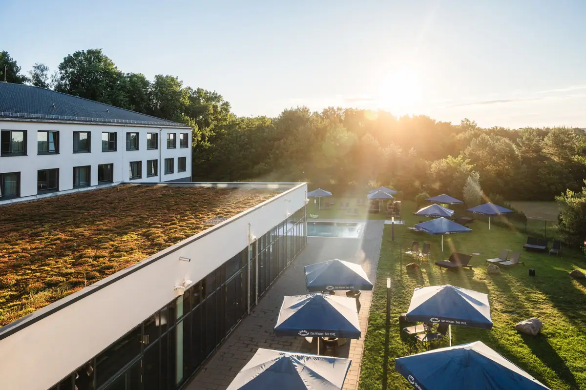 Een gebouw met parasols en stoelen op een grasveld.