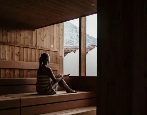 Sauna Een vrouw zit op een houten bank.