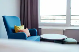 Blauwe bank met kussens en een ronde tafel voor het raam.