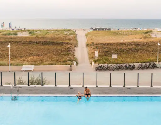 Buitenzwembad bij aja Warnemünde Een man en een kind in een zwembad.