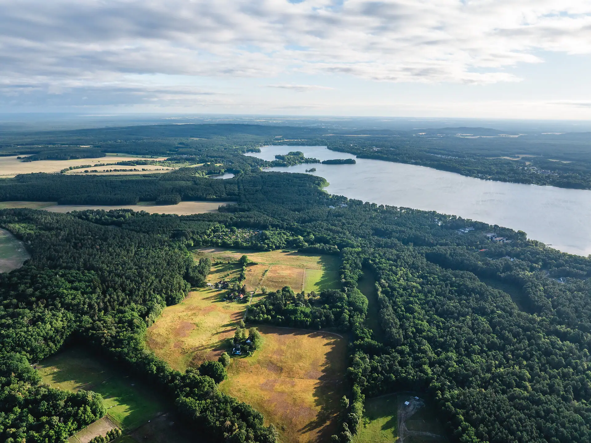 Luchtfoto van het meer en een bos met een akker vanuit vogelperspectief.