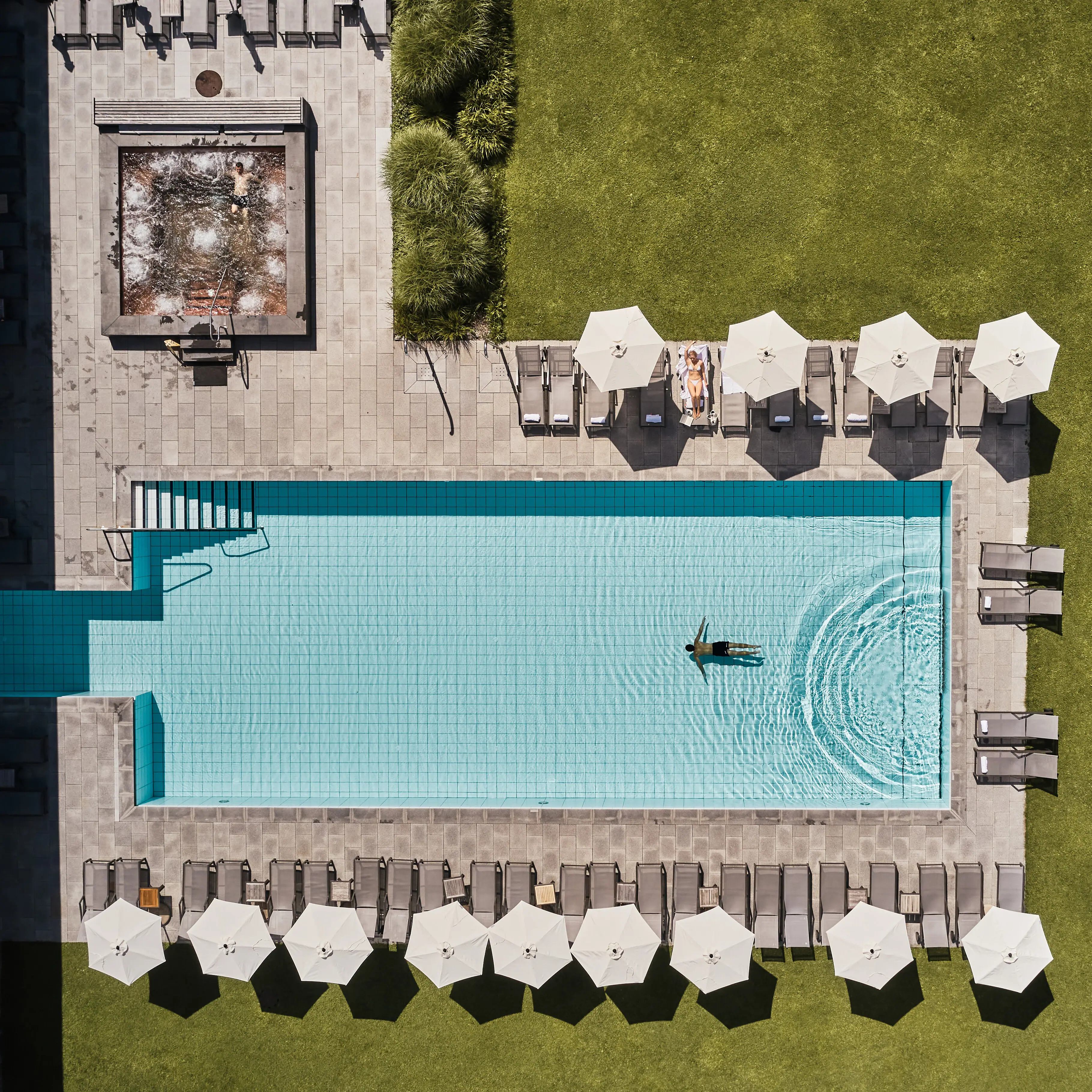 Buitenzwembad Bergresort Werfenweng Een zwembad met parasols en gras.