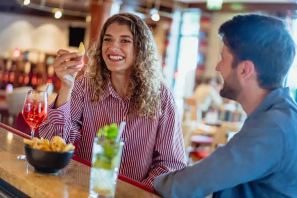 Bar Een vrouw houdt een stuk fruit vast terwijl een man aan een bar zit.