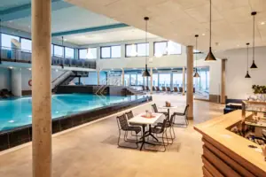 Een binnenzwembad in een gebouw met een plafond en meubilair.