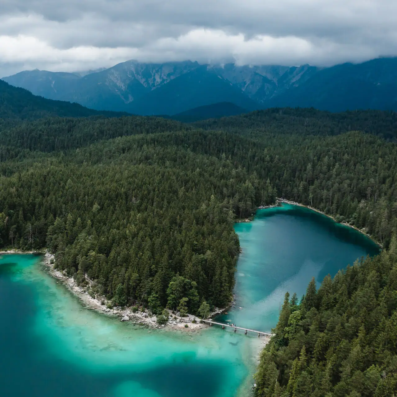 Eibsee Een watermassa met bomen en bergen op de achtergrond.
