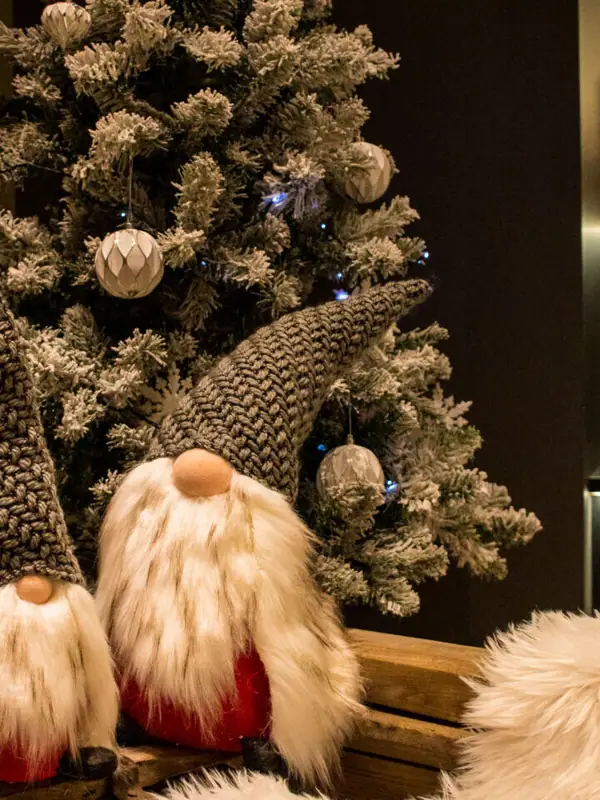 Kerstversieringen Twee elfen zitten op een bankje naast een kerstboom.