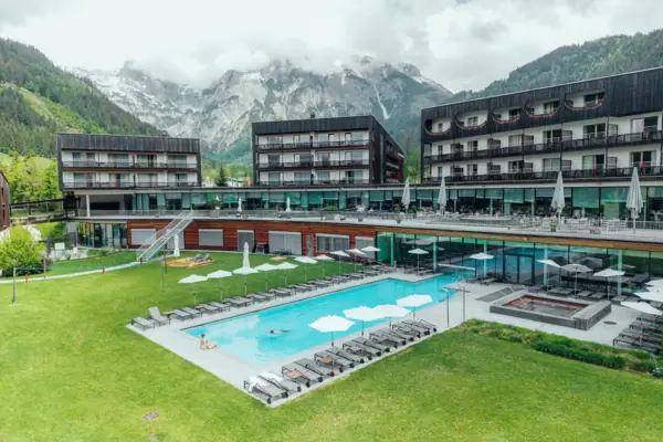 aja Bergresort Werfenweng Een buitenzwembad bij een hotel met een grasveld en bergen op de achtergrond.