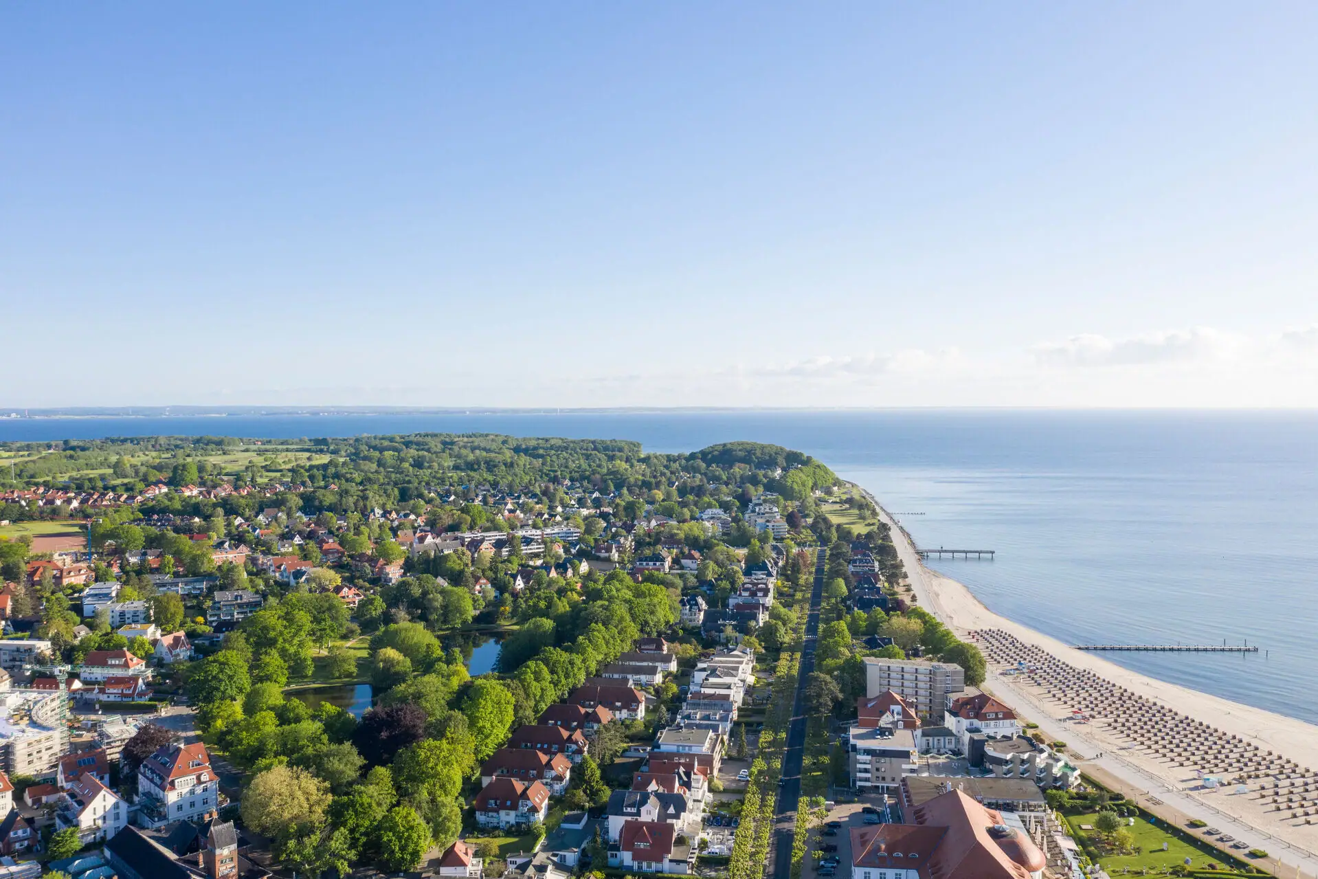 Travemünde kust Luchtfoto van een stad aan het water met gebouwen en bomen op de voorgrond.