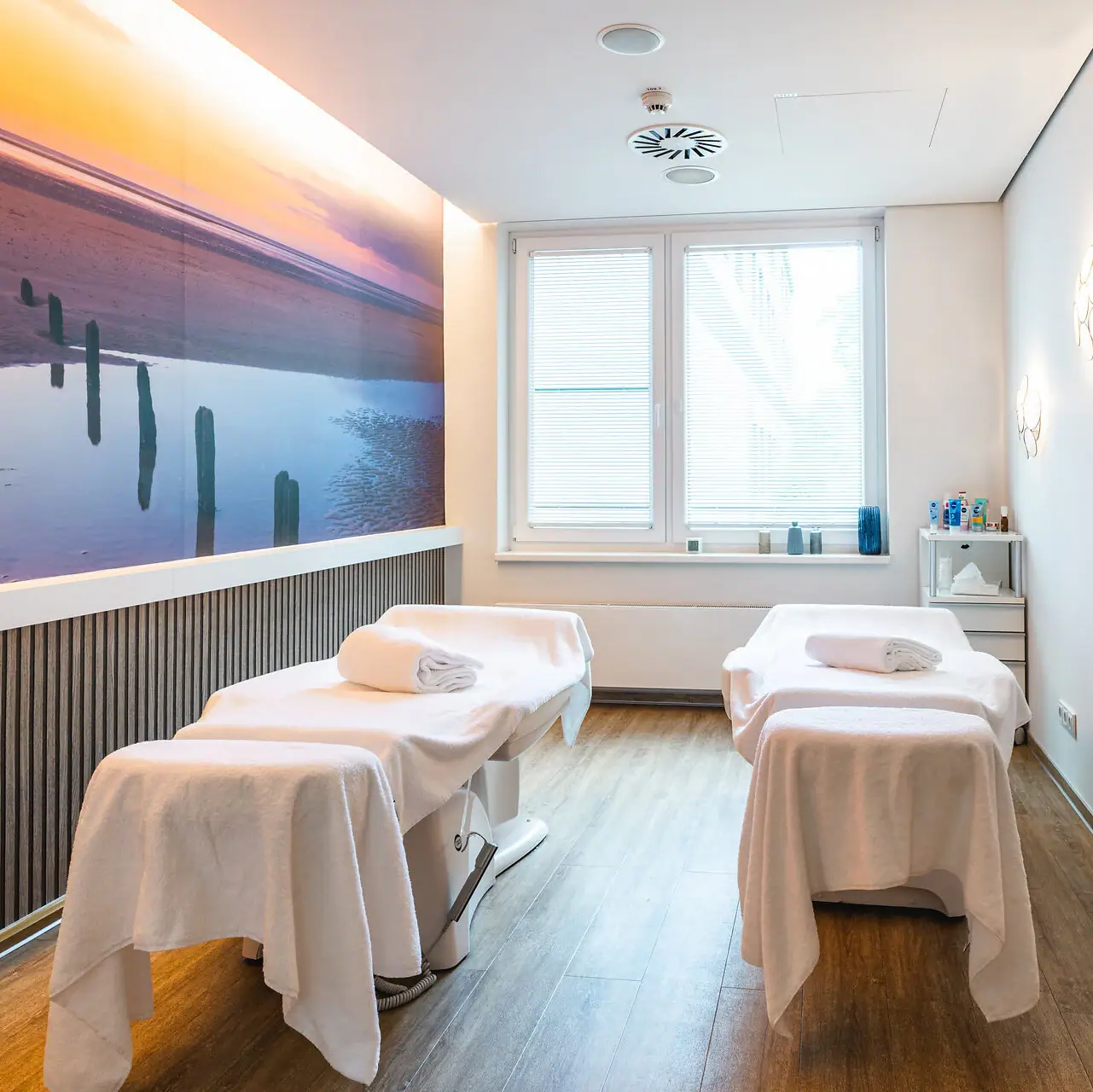 Een kamer met bedden en een schilderij aan de muur.