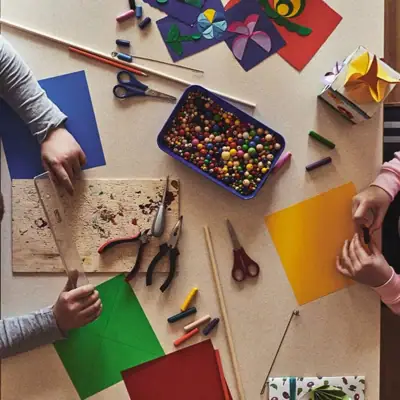 Kinderclub Een groep mensen zit aan een tafel met papier en knutselspullen.