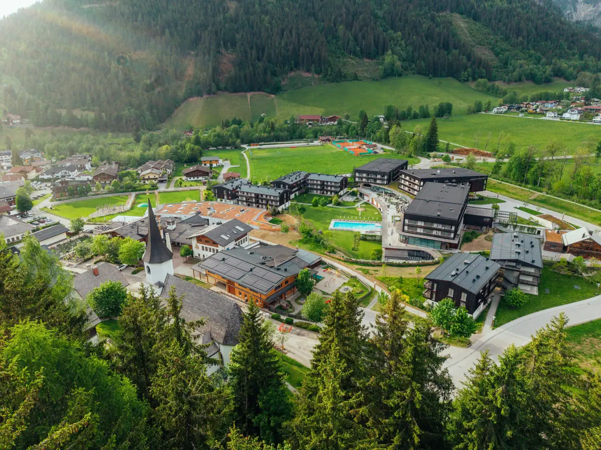 Werfenweng Mountain Resort Een stadje met veel gebouwen en een zwembad midden in een vallei.