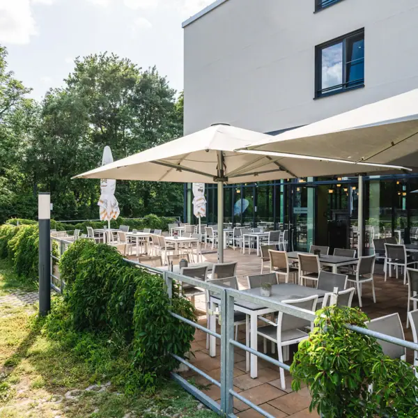 Terras met tafels en parasols voor een gebouw