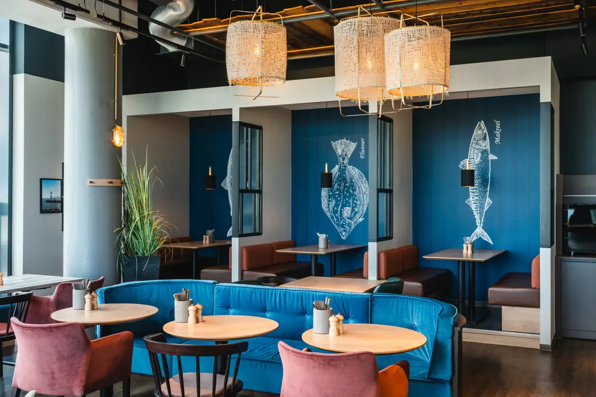 Restaurant bij aja Warnemünde Een kamer met zitnissen, ingericht in een maritieme stijl en gemeubileerd met tafels en stoelen.