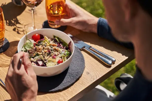 Een man eet een salade en drinkt wijn.