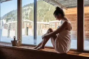 Frau sitzt auf einem Fenstersims von einer Sauna.