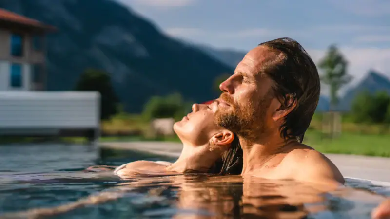 Buitenzwembad bij aja Ruhpolding Een man en een vrouw in een zwembad.