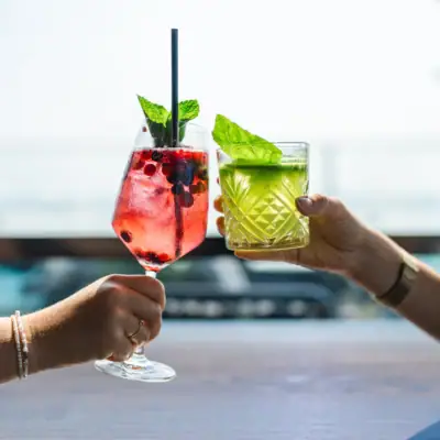 Twee handen houden drankjes met rietjes vast.