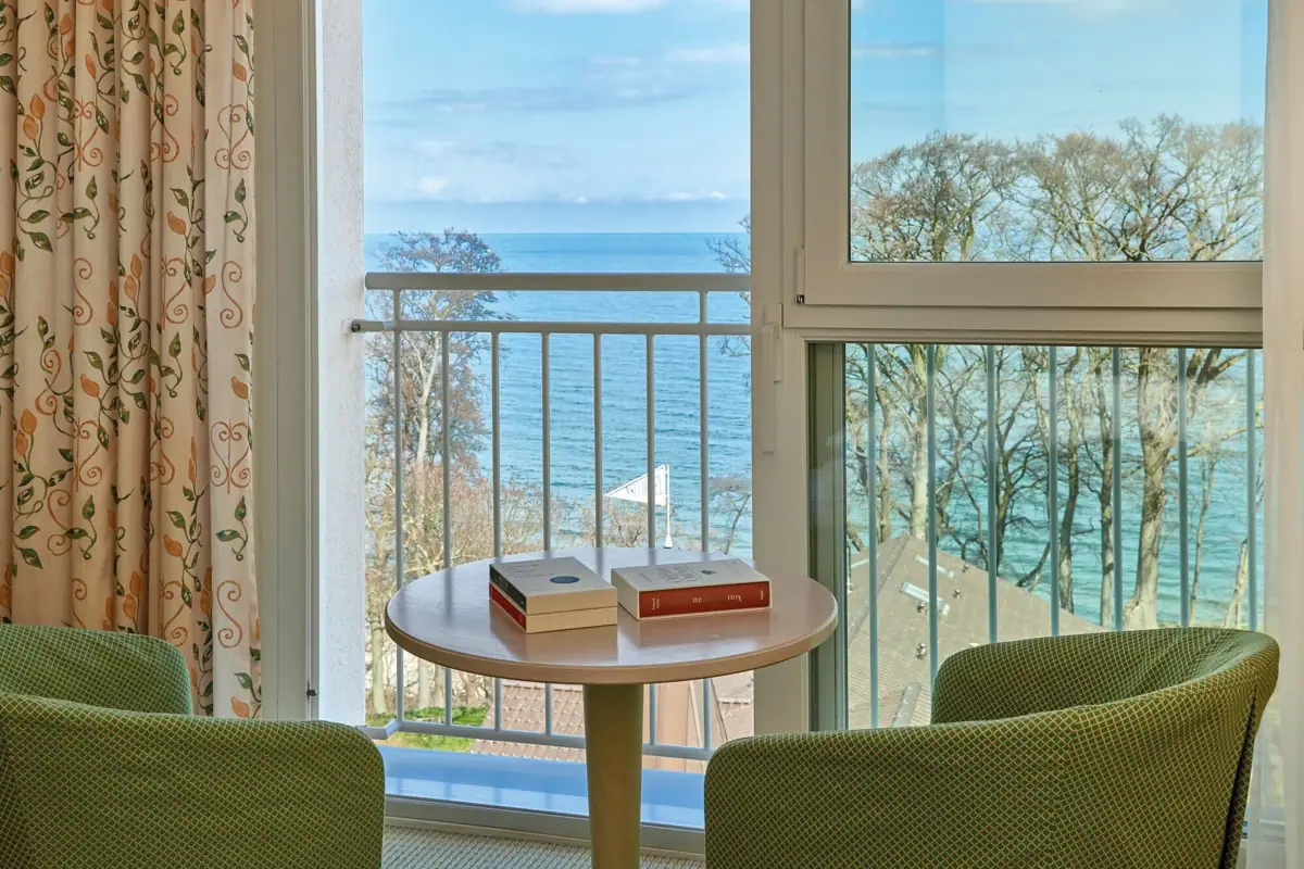 Een tafel met boeken erop, voor een balkon met uitzicht op de oceaan.