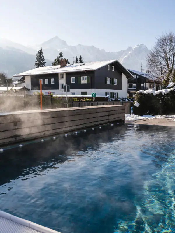 Buitenzwembad in de sneeuw Een dampend buitenzwembad met bomen op de achtergrond.