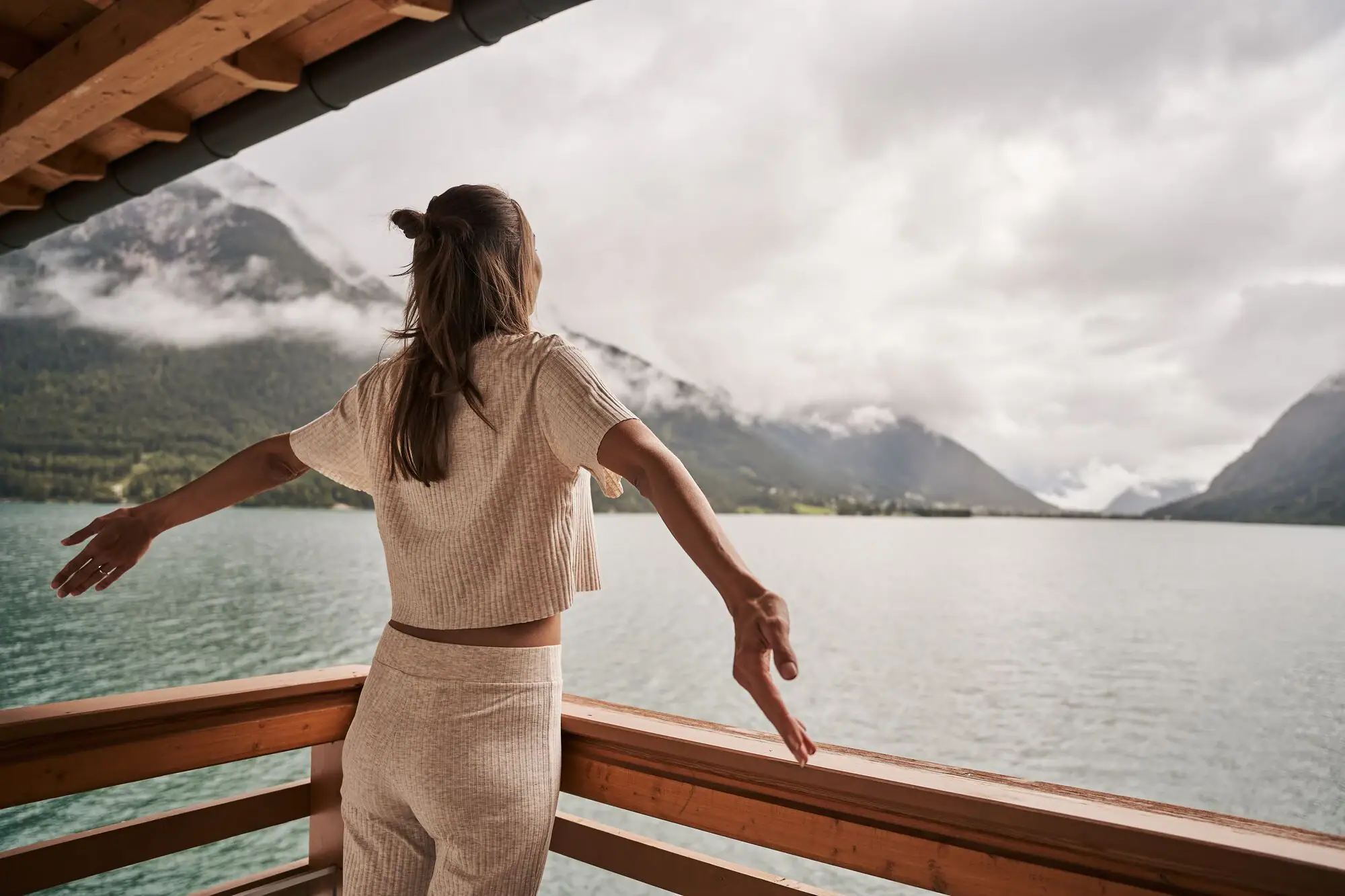 Vrouw op het balkon aan het Achenmeer Een vrouw staat op een balkon dat uitkijkt over het water.