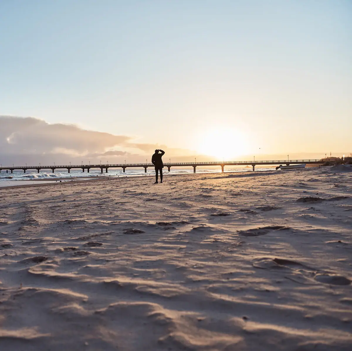 Strand Een persoon loopt langs het strand onder een bewolkte hemel.