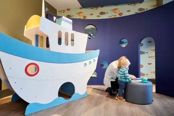 Speelkamer bij aja Warnemünde Een vrouw en een kind spelen met een speelgoedschip.
