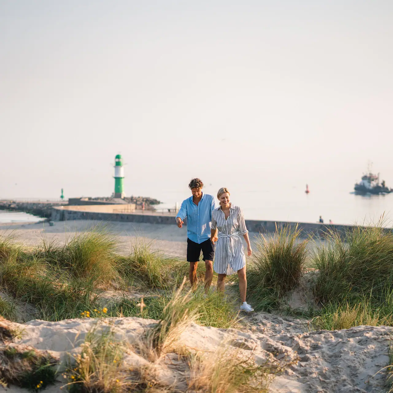 Ervaringen bij aja Warnemünde Een man en een vrouw lopen langs het strand.