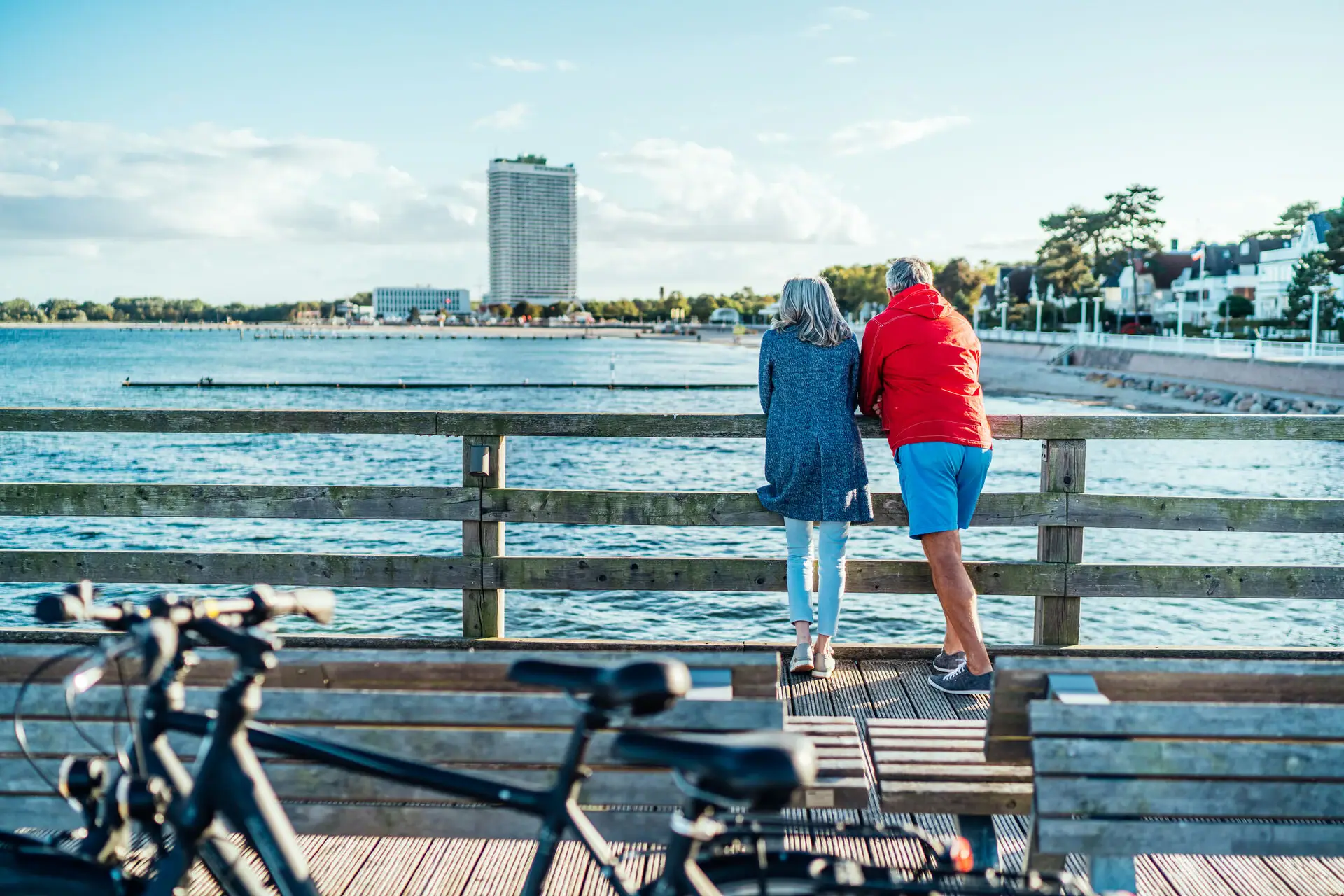 Paar aan zee Een man en een vrouw staan op een houten brug en kijken uit over het water.