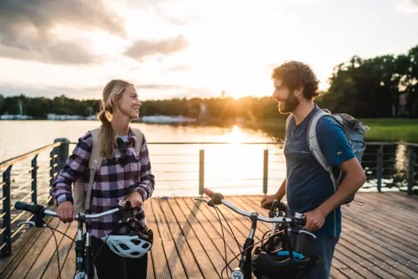 Een man en een vrouw staan met fietsen op een steiger voor een meer.