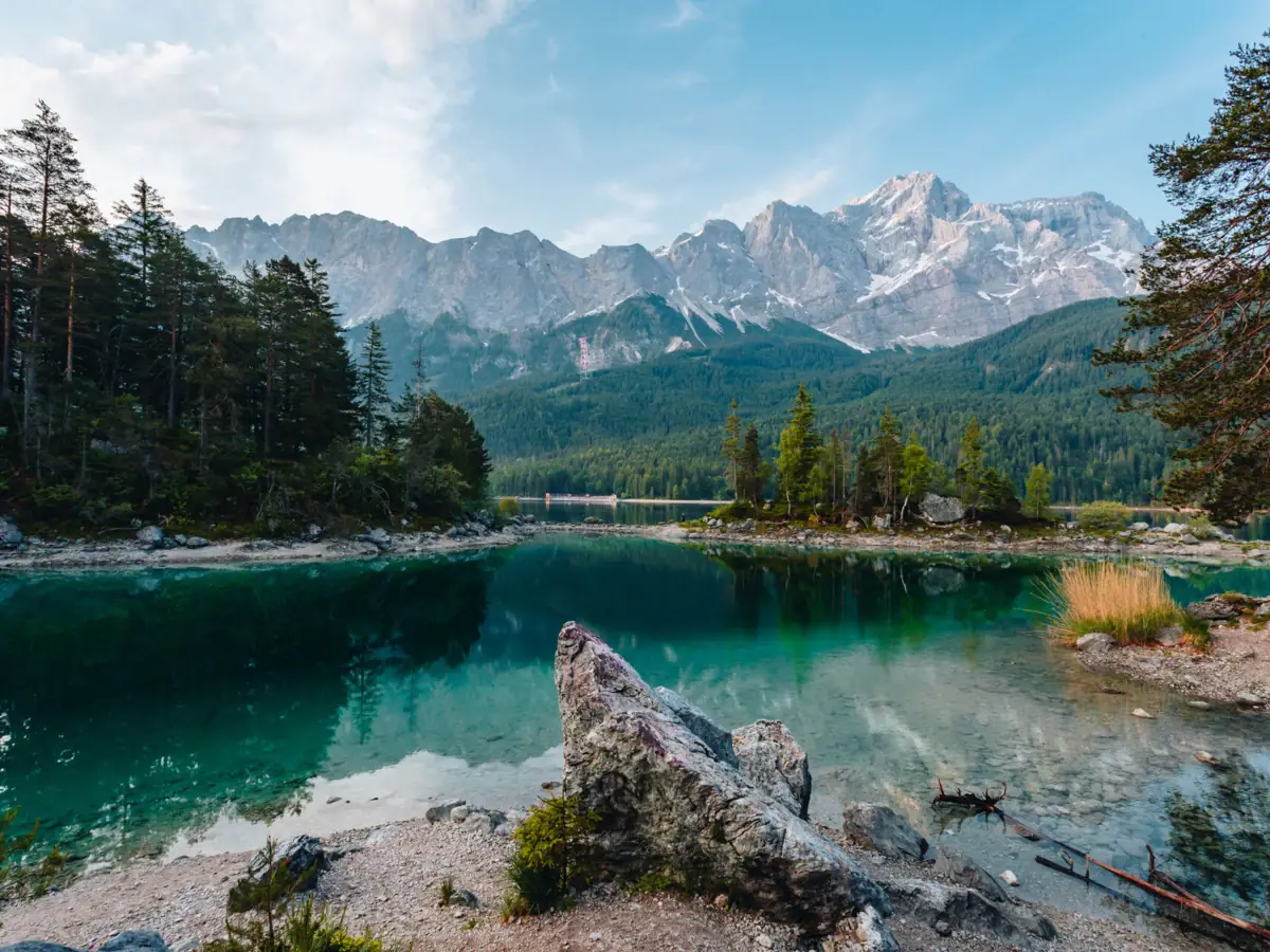 De Eibsee Een meer met bomen en bergen op de achtergrond.