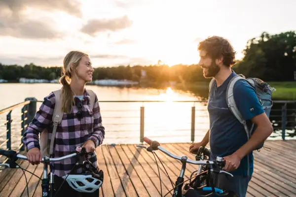 Fietstocht Een man en een vrouw staan met fietsen op een steiger voor een meer.