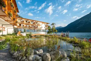 Ein Gebäude vor einem Gewässer mit Bergen im Hintergrund.