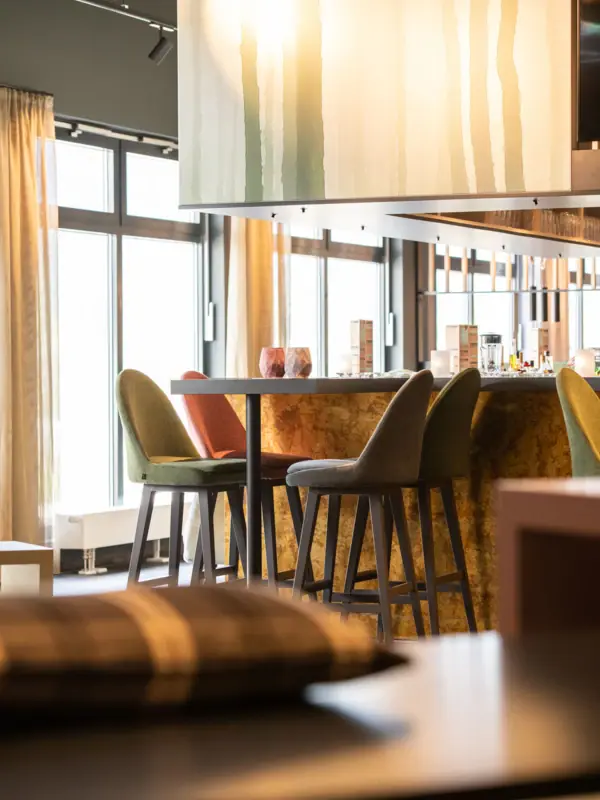 aja Bar Ruhpolding Een kamer met een bar en stoelen.