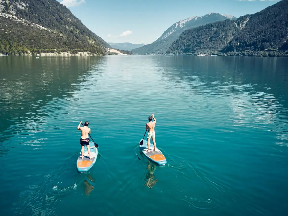 SUP op de Achensee Twee mannen op waterfietsen op een meer.