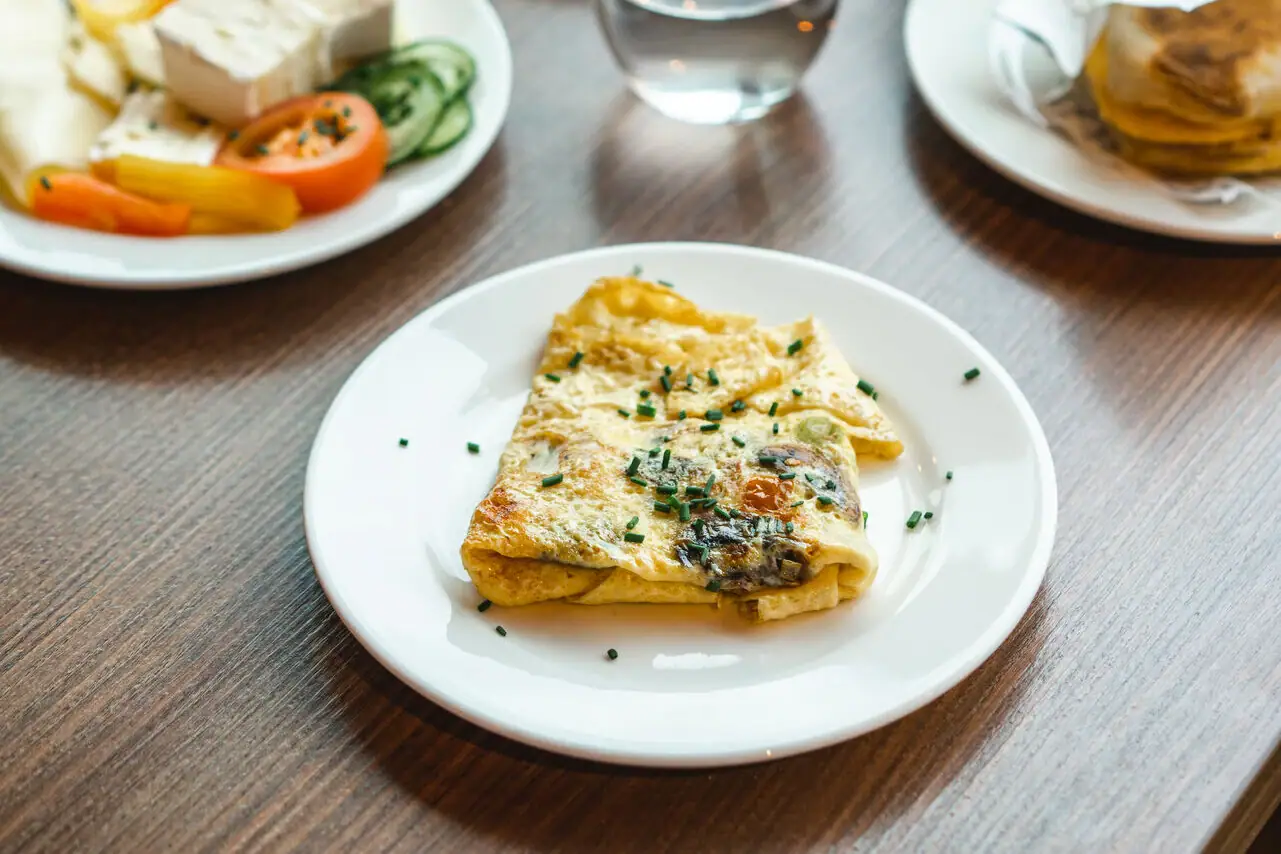 Een ontbijttafel met borden vol eten en drinken.
