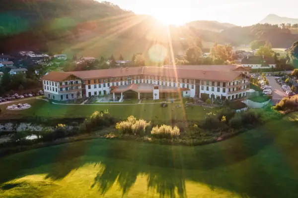Een groot gebouw met een groot grasveld en een parkeerplaats op de voorgrond.