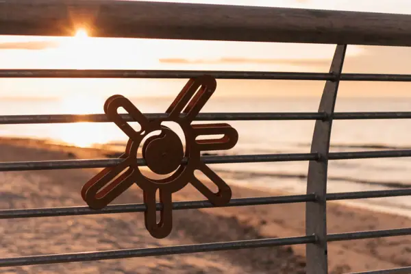 Metalen leuning met daarop een zonnesymbool.